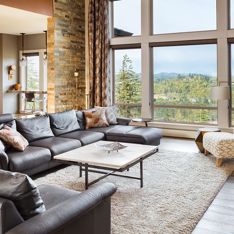 Great room with floor-to-ceiling windows, exposed brick column and wide-plank flooring
